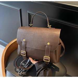 Brown vintage satchel bag with litchi grain texture and gold buckles on a black chair