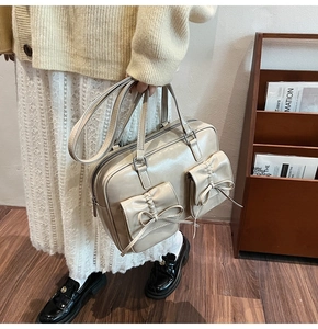 Detail of beige PU leather handbag with dual bow pockets and pleated flap design