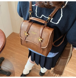 Detail of vintage brown leather mini backpack with gold star accents and carry handle