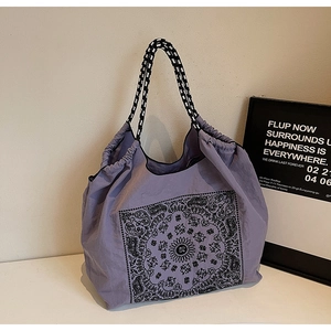 Detail of purple paisley tote bag with woven handles and drawstring closure mechanism
