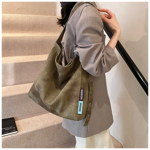 Detail of olive green canvas tote bag showing textured fabric and branded side label