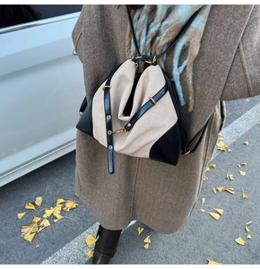 Outdoor shot of a beige oversized bag with black leather straps and gold metal hardware