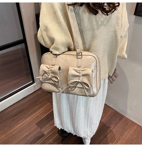 Detail of beige PU leather shoulder bag featuring dual pockets and delicate bow accents
