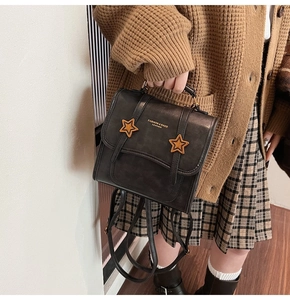 Detail of a black leather mini backpack with gold star accents on a stylish outfit