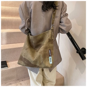 Detail of vintage canvas tote bag with woven logo labels on a khaki textured surface