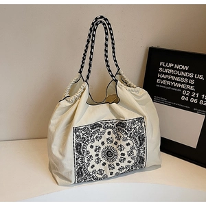 Detail of canvas tote bag with paisley print, drawstring closure and woven handles