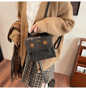 Detail of dark grey retro crossbody bag with golden star buckles and matte leather texture