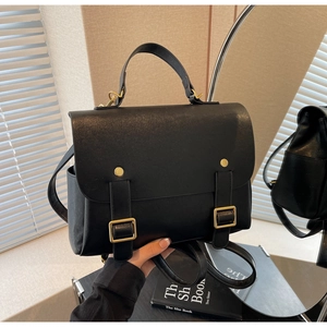 Detail of vintage black leather backpack showing gold buckles and top handle texture