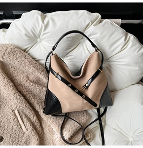 Close-up of the beige suede tote bag with black strap and golden metal eyelets