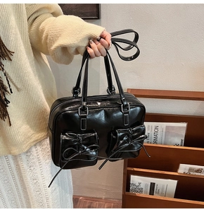 Detail of black PU leather bag with white contrast stitching and bow-decorated flap pockets