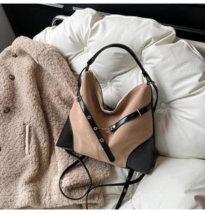 Detail of hobo bag with khaki suede and black leather stitching with gold metal hardware