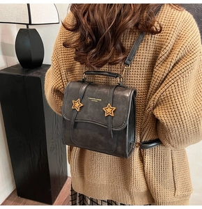 Detail of a charcoal gray retro backpack featuring golden star studs and leather texture