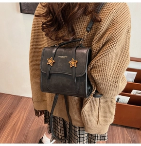 Detail of vintage grey leather backpack featuring golden star buckles and leather texture