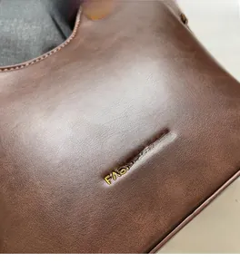 Close-up of pebble grain brown leather texture with gold stamped logo on bucket bag
