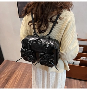 Close-up of black patent leather backpack featuring vintage 3D bow and white stitching detail