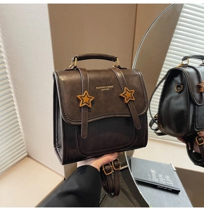 Detail of vintage brown leather bag with star accents and dual straps in mirror reflection