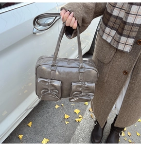 Detail of vintage grey-brown leather Boston bag with bow pockets and double straps