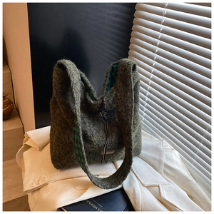 Détail d'un sac cabas en peluche vert foncé avec doublure à carreaux et petite étiquette