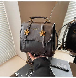 Detail of dark brown leather backpack with gold star accents and fashion lettering