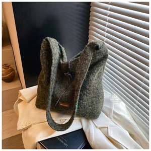 Détail du sac fourre-tout en peluche verte avec écusson logo en cuir sur blazer blanc