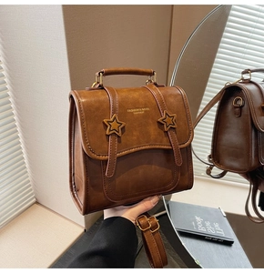Macro shot of retro brown matte leather backpack with star buckle details in a mirror reflection