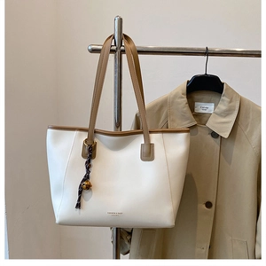 Dettaglio borsa shopper bianca con manici marroni e ciondolo viola in esposizione