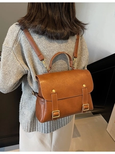 Retro brown leather backpack with gold hardware and top handle shown on a model