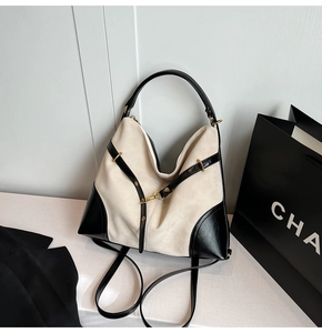 Close-up of cream suede and black leather bag with gold studs and cross strap detail