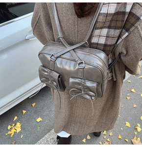 Gray glossy vintage backpack detail featuring double pockets with ribbon bows and folds