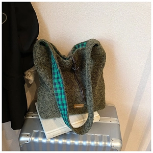 Détail du sac fourre-tout en peluche vert foncé avec doublure à carreaux et logo