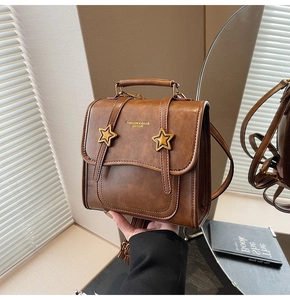 Detail of vintage brown leather bag featuring gold star accents and fashion engraving