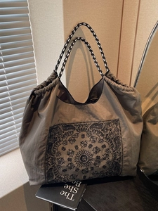 Vintage dark green tote bag with paisley pattern and braided rope handles in soft light