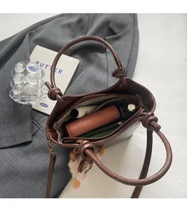 Spacious interior of brown bucket bag showing daily essentials and zip pocket detail