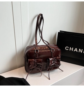 Detail of dark burgundy glossy patent leather bag with two bow-knot drawstring pockets