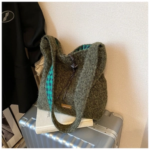 Détail d'un cabas vert en peluche avec doublure à carreaux et cordon en cuir