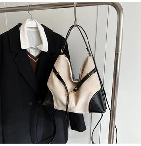 Detail of a large cream and black tote bag featuring gold hardware and long straps