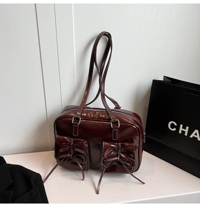 Detail of glossy patent leather handbag featuring bow-decorated pockets and silver zipper