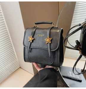 Close-up of black leather bag with gold star buckles and mirror reflection detail