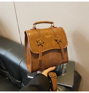 Detail of retro brown leather crossbody bag featuring gold star buckles and handle