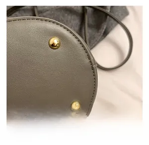 Close-up of golden metal base studs and premium textured gray leather with neat stitching