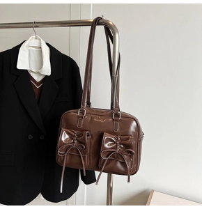 Detailed view of dark brown glossy patent leather shoulder bag with bow-knot pocket details