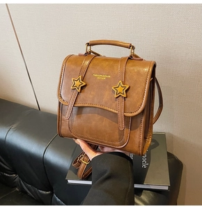 Close-up of a vintage brown leather backpack with distinctive yellow star charms and gold logo