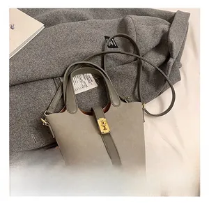 Detail of grey bucket bag with golden twist lock on wool fabric and magazines