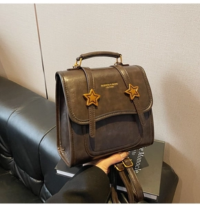Close-up of vintage brown leather dual-use bag featuring gold stars and logo detail