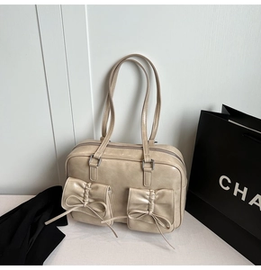 Detail of vintage beige faux leather tote with decorative bow pockets and silver hardware