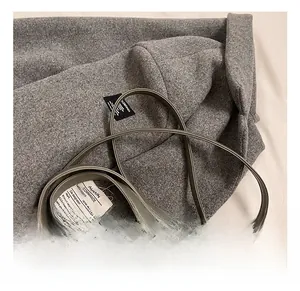Detail showing high-quality light grey wool texture and slim leather handles on the tote bag
