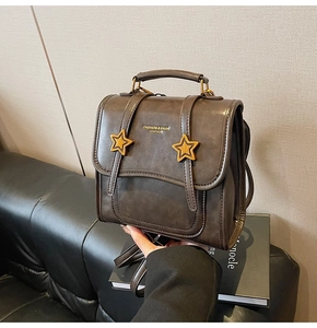 Detail of vintage coffee leather handbag featuring gold star badges and handle