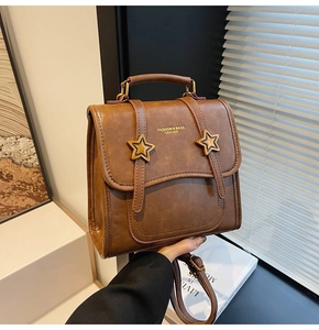 Detail of a brown leather bag with metal star accents and elegant gold embossed text