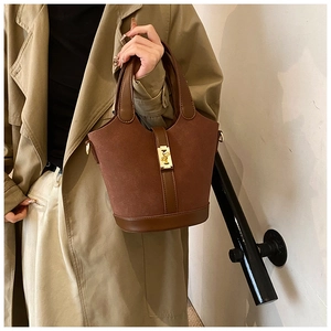 Detail of vintage brown bucket bag with gold lock closure and suede leather texture