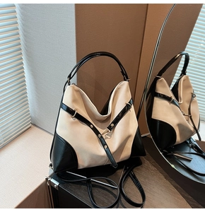 Detailed mirror view of a black and beige contrast handbag with metal rivet accents